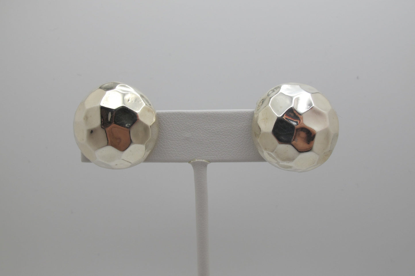 Pair of silver round stud earrings on a gray background