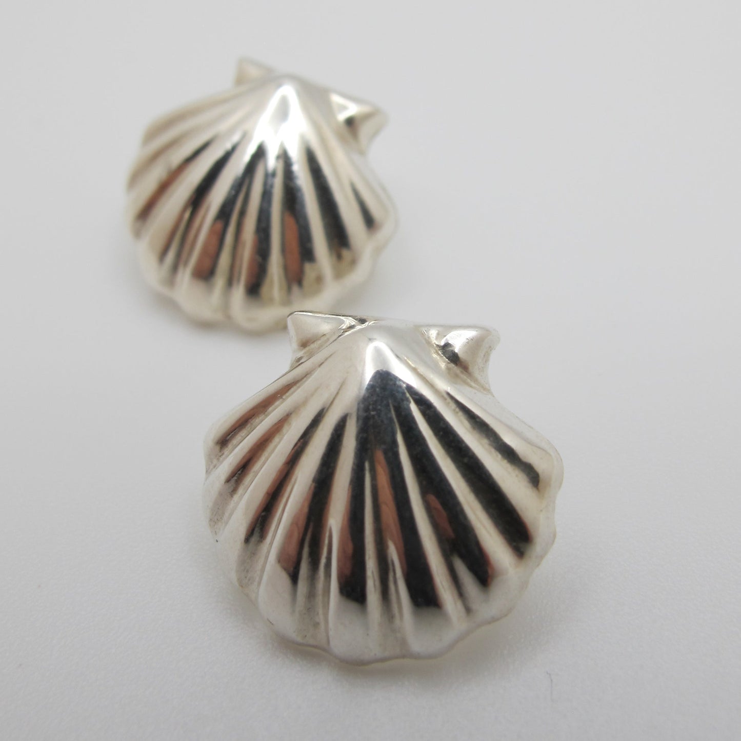 Silver shell-shaped earrings on a white background