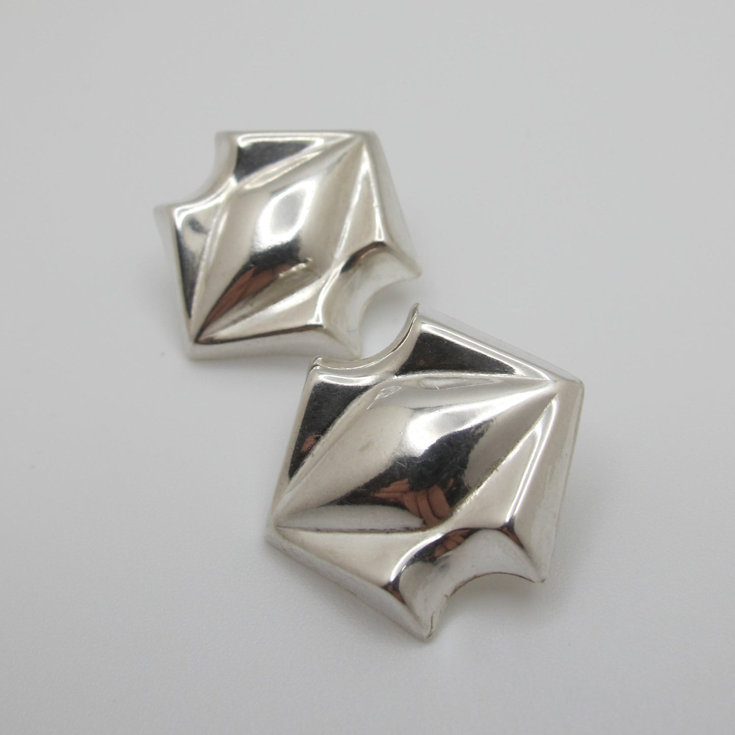 Pair of silver geometric earrings on a white background