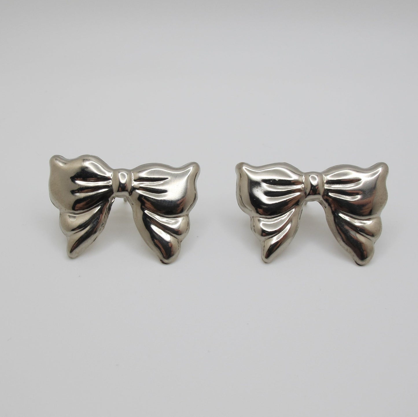 Silver bow-shaped earrings on a white background