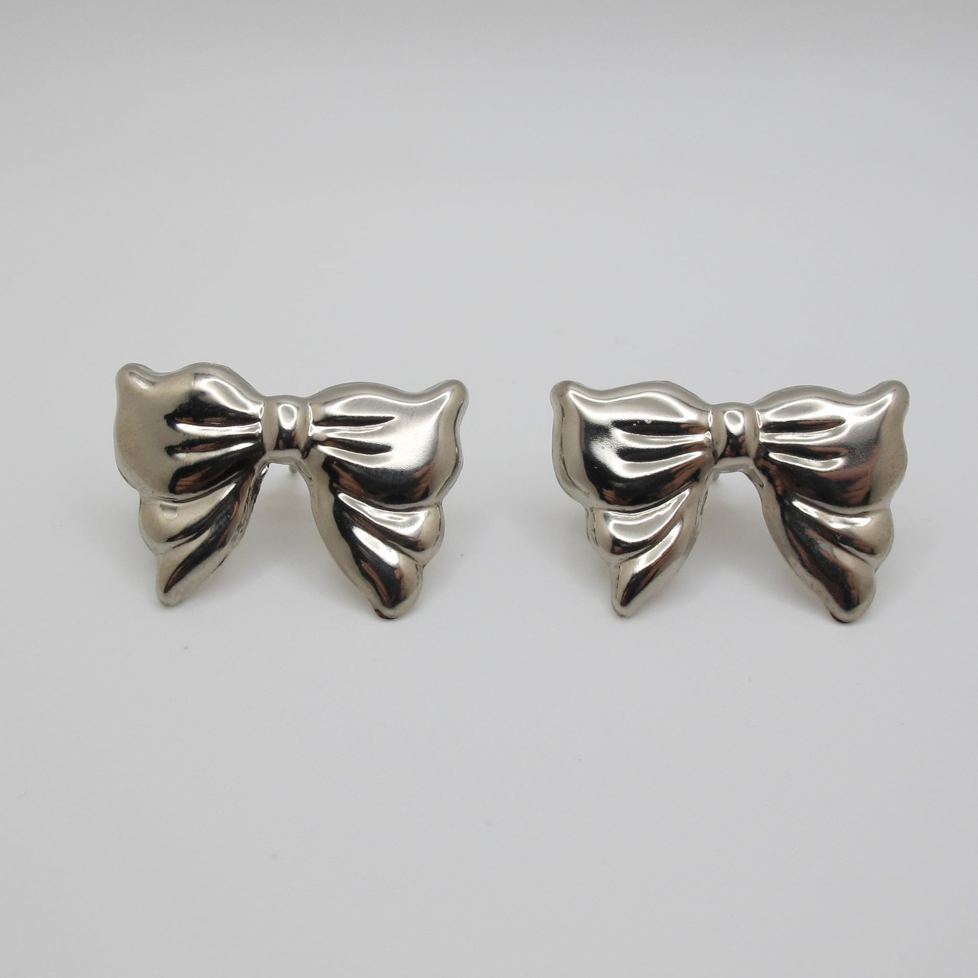 Silver bow-shaped earrings on a white background