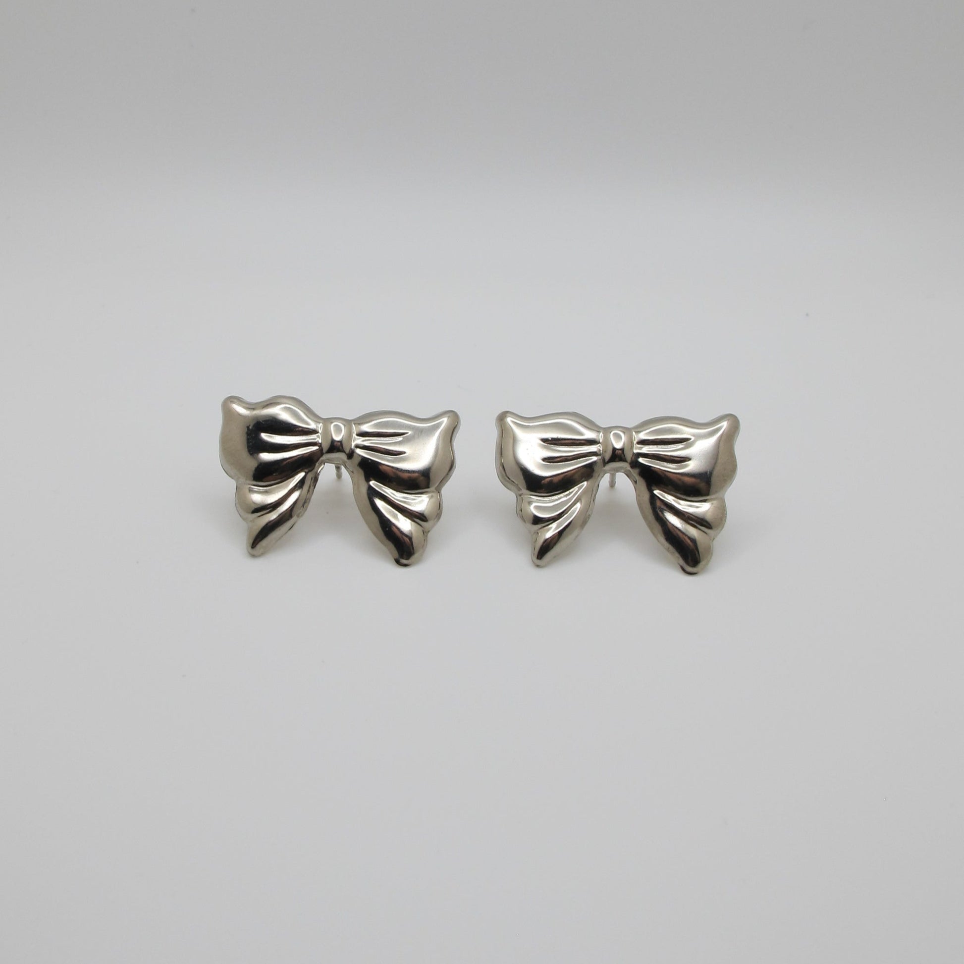 Pair of silver bow-shaped earrings on a white background