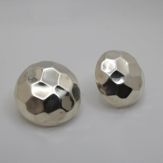 Two metallic, faceted sphere earrings on a gray background