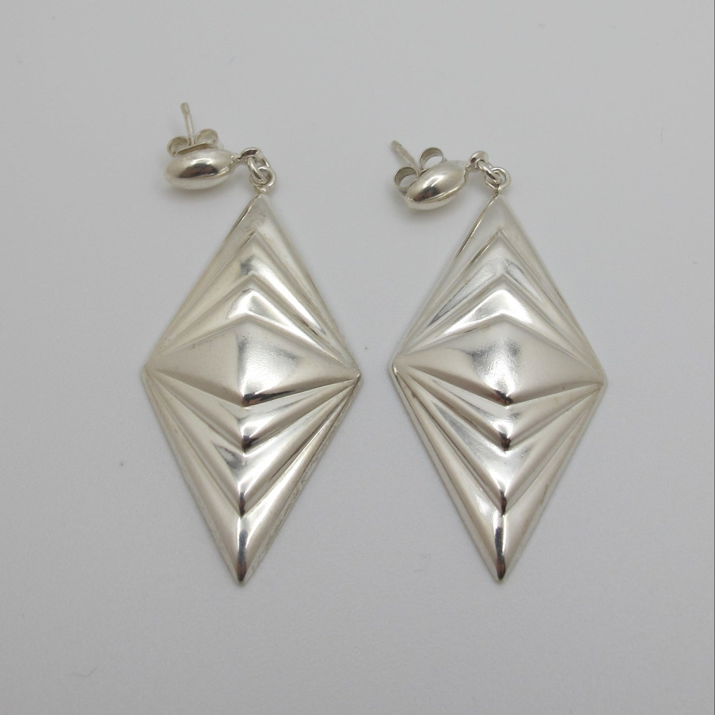 Pair of silver geometric earrings on a light gray background