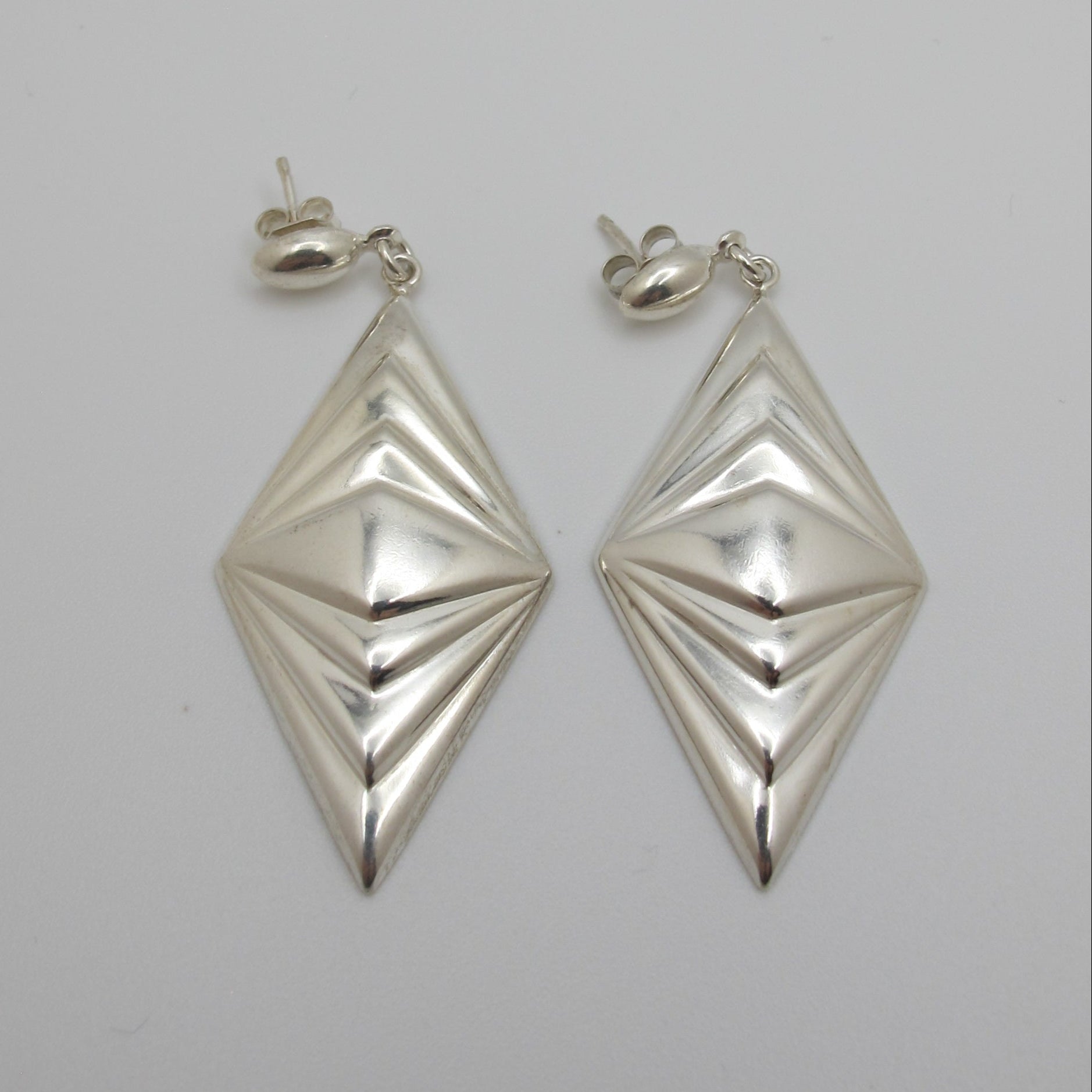 Pair of silver geometric earrings on a light gray background