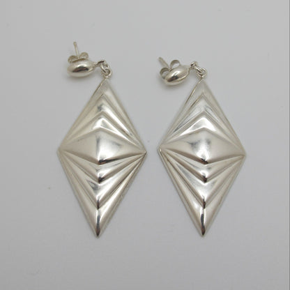 Pair of silver geometric earrings on a light gray background