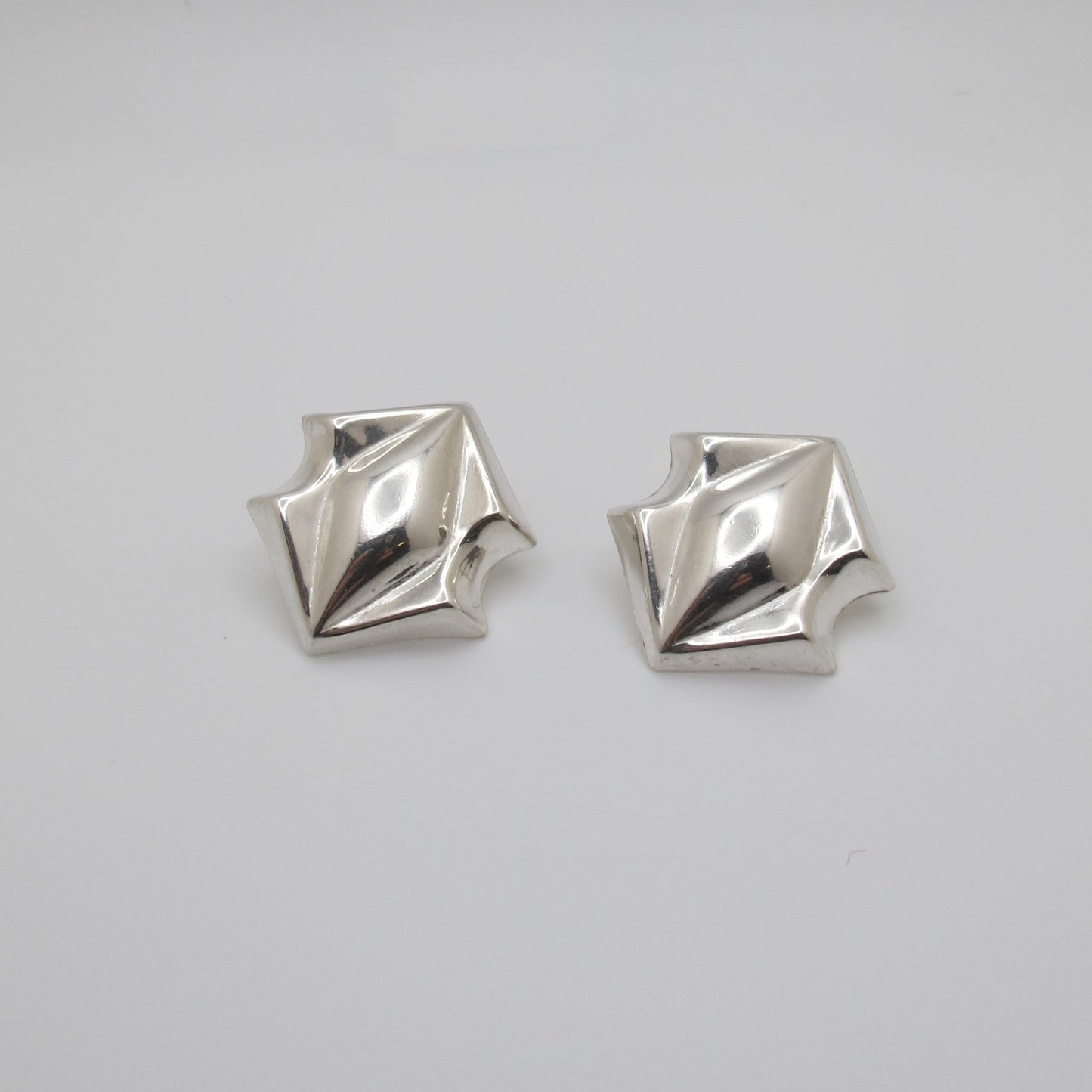 Pair of silver geometric earrings on a white background