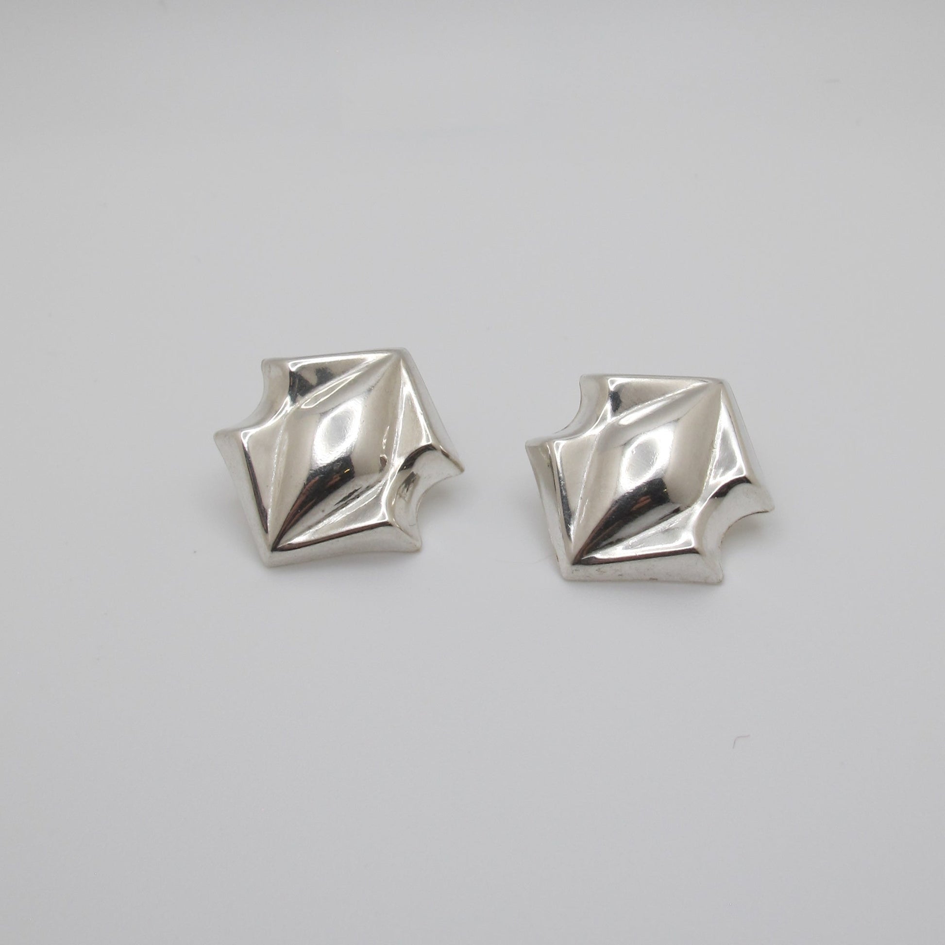 Pair of silver geometric earrings on a white background